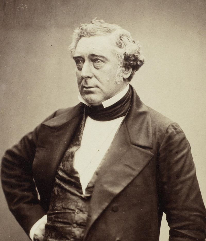 Black and white picture of Robert Stephenson. He's looking off to the left on a blank background wearing a white shirt with a velvet waistcoat and a dark suit top. 